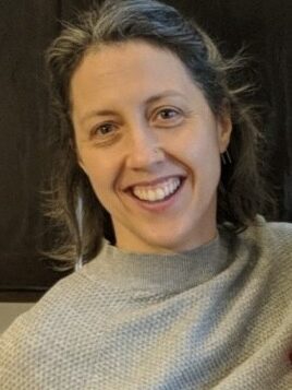 Hilary Otey, a white woman with shoulder-length hair, wearing a light-colored sweater, smiles at the camera.