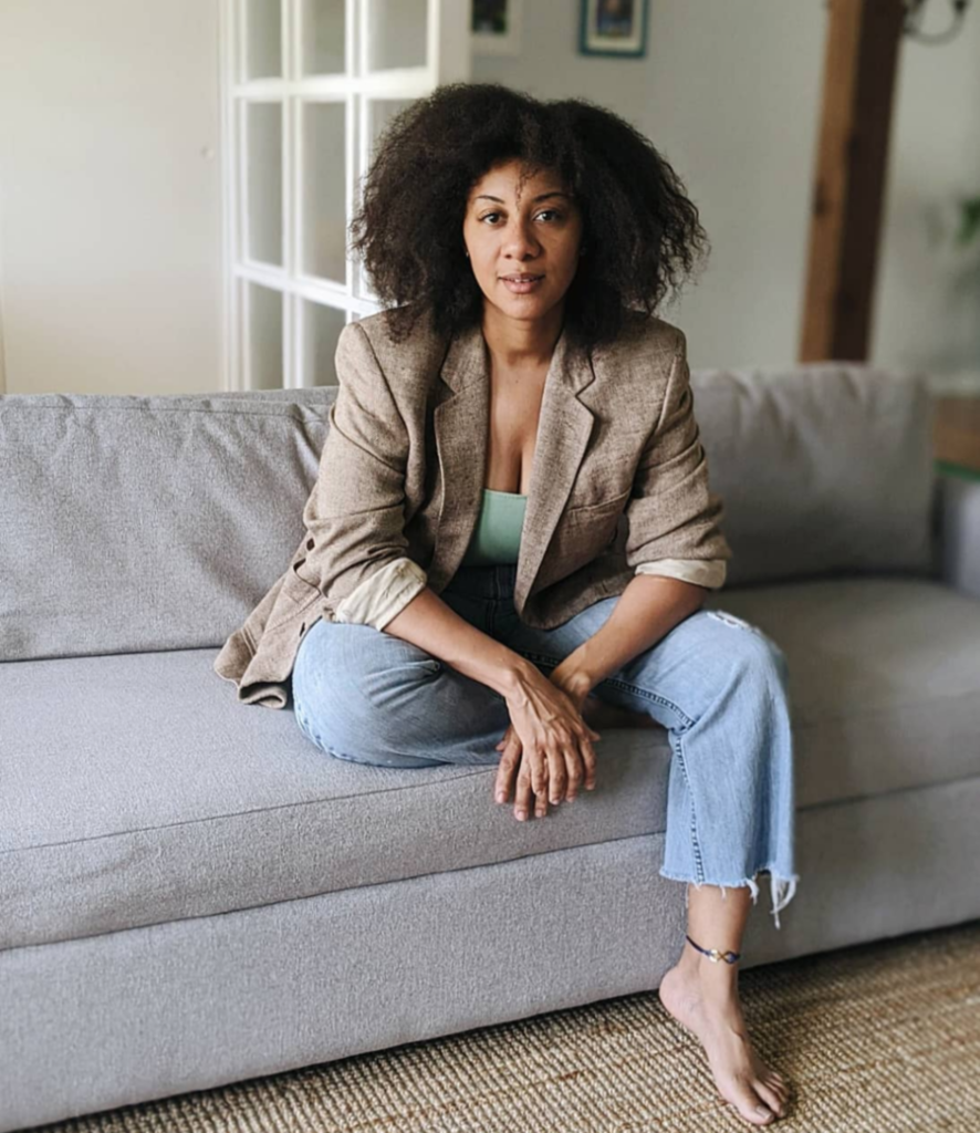 A Black woman sits on a couch.