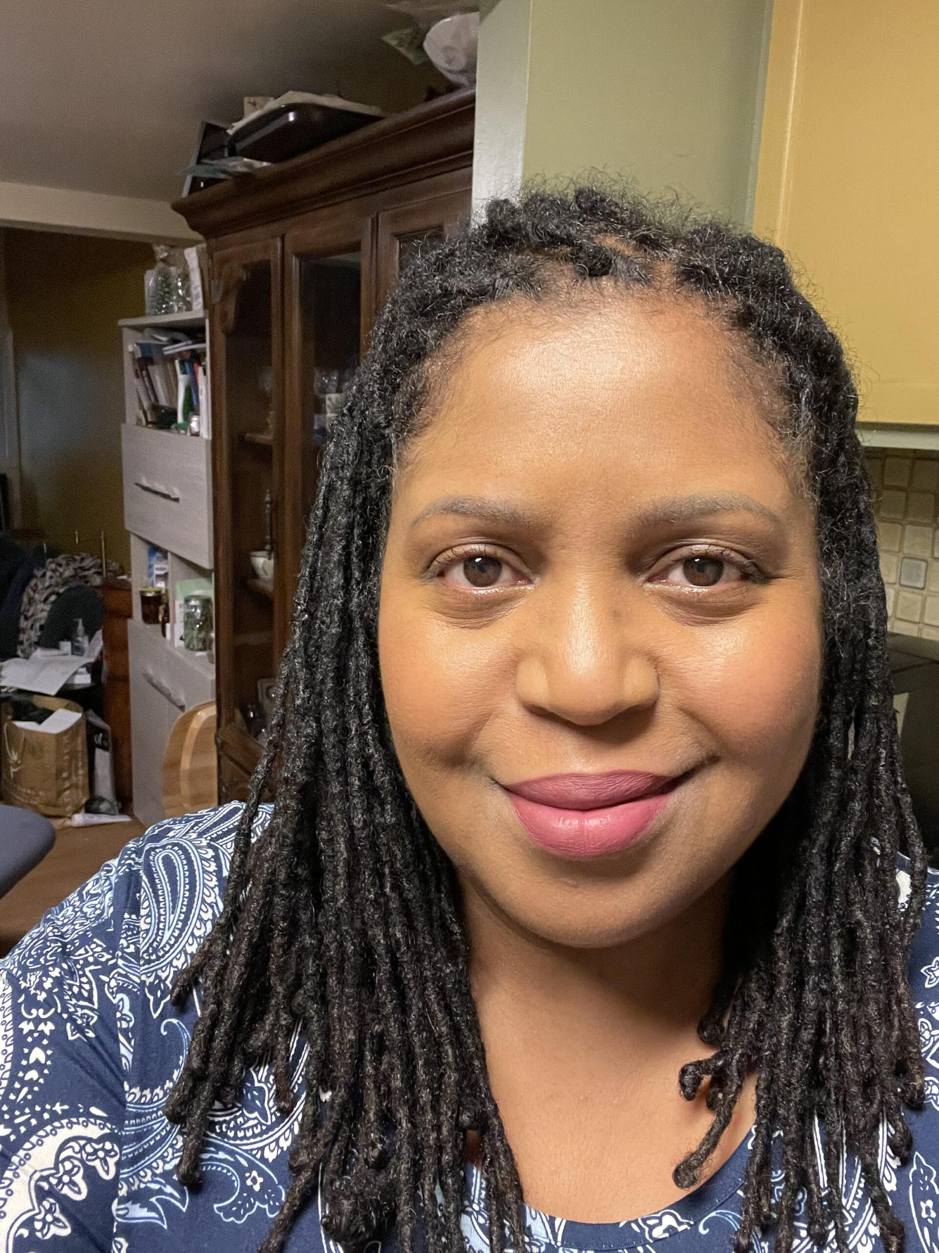 Carla Gates, a Black woman with locs, smiles at the camera.